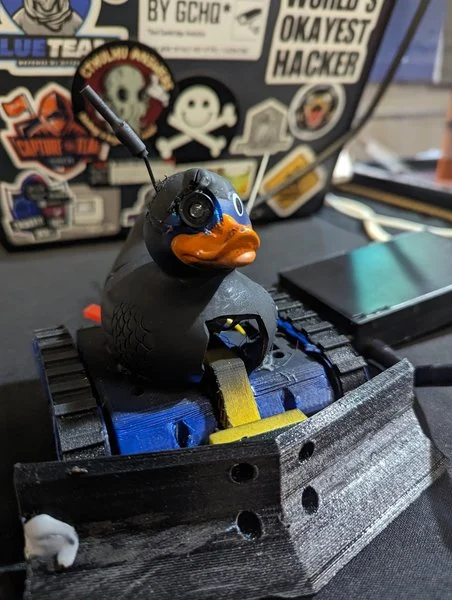 A small wheeled robot with a rubber duck and antenna, photographed at Farset Labs