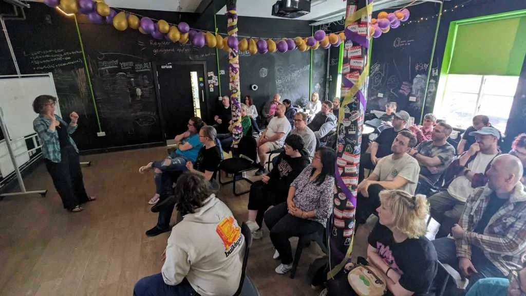A speaker with knitted props talking to the audience at a Farset Labs ELI5 night